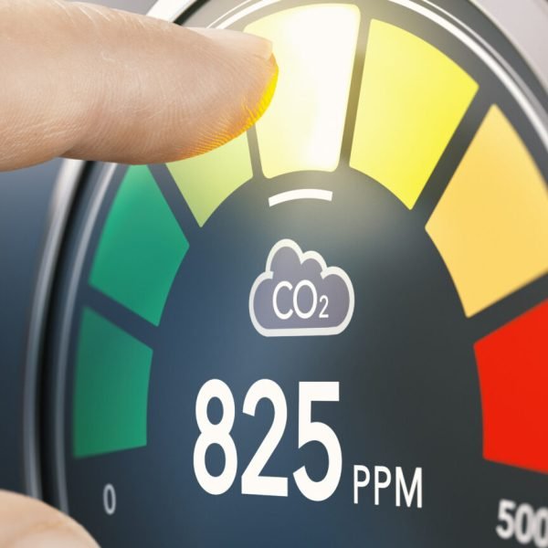 Finger touching digital screen of a CO2 monitor to measure indoor air quality and carbon dioxide concentration. Composite image between a hand photography and a 3D background.